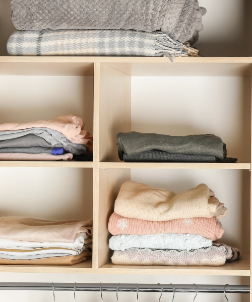 A shelf filled with folded clothes and blankets